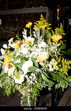 Gelbe und weiße Blumen schaffen ein wunderschönes Arrangement in einer Kirche Stockfoto
