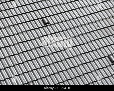 Nahaufnahme der grauen Dachziegeloberfläche mit sich wiederholenden Keramikrippen und klaren geometrischen Linien, die langlebige Dachkonstruktion und Textur zeigen Stockfoto