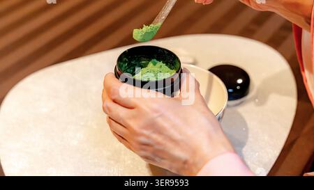 Nahaufnahme der Hände, die während einer traditionellen japanischen Teezeremonie in Tokio, Japan, Matcha zubereiten, mit grünem Tee in einem Lackbehälter auf einer Tat Stockfoto