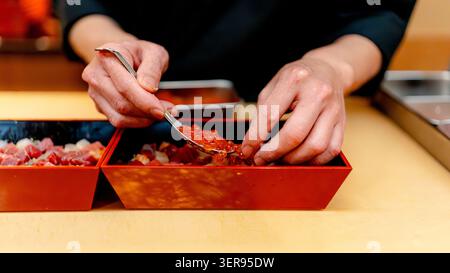 Nahaufnahme eines Küchenchefs in einem japanischen Restaurant in Tokio, der Chichashi-Sushi mit Miyagi Pacific Rotem Thun, Meeresfrüchten und Lachskaviar arrangiert. Stockfoto