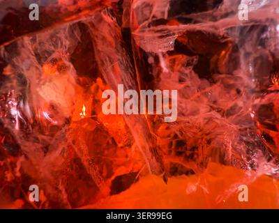 Extreme Nahaufnahme eines Aperol-Cocktails mit prickelndem Orangengetränk und durchscheinenden Eiswürfeln. Lebendige Rot-Orange-Töne sorgen für einen erfrischenden Sommer Stockfoto