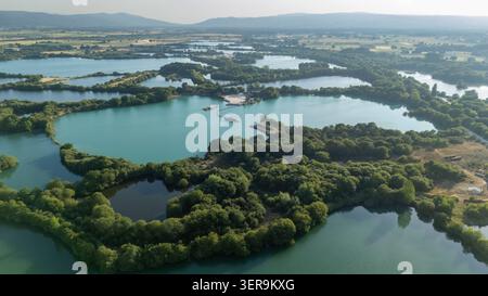 Aus der Vogelperspektive zeigt eine Kiesgrubenindustrie, die miteinander verbundene Seen schafft und die Landschaft in Sandias, Ourense, Galicien, Spanien verändert Stockfoto