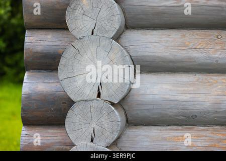 Nahaufnahme einer verwitterten Blockhüttenecke mit Rissen, rustikalen Holztischlerei und grauer Holzstruktur mit natürlicher Maserung, die ländlich wirkt Stockfoto