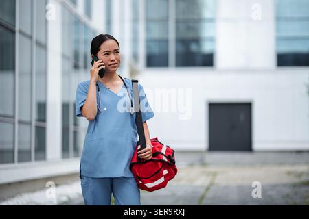 Krankenschwester, die telefoniert und erste-Hilfe-Tasche hält Stockfoto