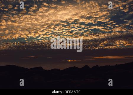 Sonnenuntergang über dem Meer mit Wolken und felsigem Ufer, Blick von der Küste am Abend. Der Himmel ist während des Sonnenuntergangs mit Wolken gefüllt. Die Sonne geht am Horizont unter, casti Stockfoto