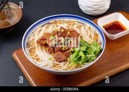 Chinesische geschmorte Rindfleisch-Nudelsuppe mit grünem Gemüse. Traditionelles asiatisches Rindfleisch, orientalisches Komfortessen auf Holzbrett. Stockfoto