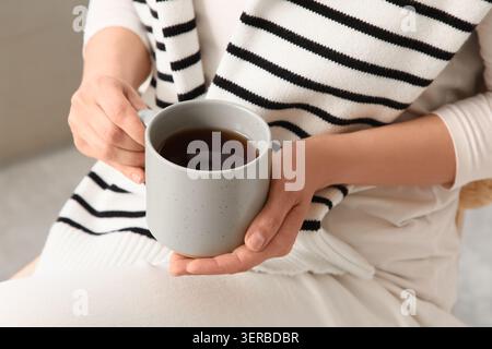 Frauenhände halten eine warme, graue Tasse heißen Tee oder Kaffee, gemütlicher Komfort und Entspannung Stockfoto