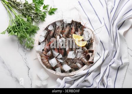 Tablett mit frischen Garnelen, Eis und Zitrone auf Marmorhintergrund Stockfoto