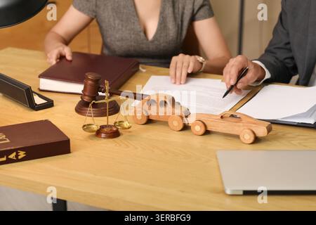 Hölzerne Autos mit Justizwaage und Richter auf dem Tisch der Anwälte im Amt, Nahaufnahme Stockfoto