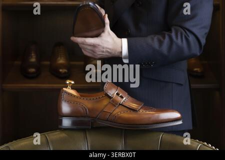 Brauner Vollnarbenleder-Schuh vor einer Holzausstellung im Herrenschuhladen Stockfoto