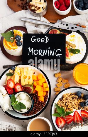 Frühstück mit Kaffee, Orangensaft, Käseplatte, Müsli, Obst und Müsli auf hellem Hintergrund. Draufsicht. Stockfoto
