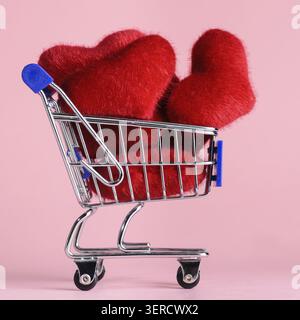 Warenkorb voller Herzen zum Valentinstag auf rosa Hintergrund Stockfoto