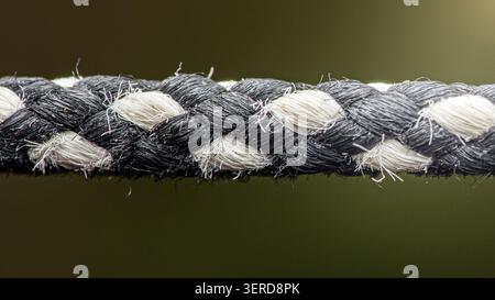Geflochtenes Seil mit verflochtenen schwarzen und weißen Litzen. Betonung von Festigkeit, Verbindung und textilem Material. Thailand Fotografie, keine g Stockfoto