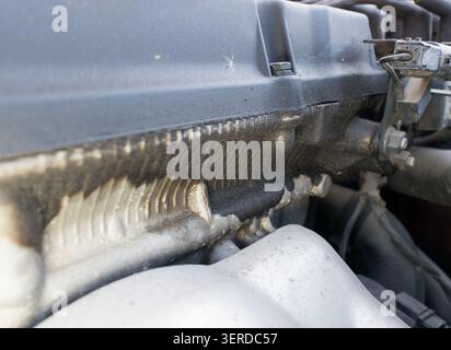 Detaillierte Nahaufnahme eines Pkw-Motors mit einer erheblichen Ölleckage an der Ventildeckeldichtung, die angesammelten Schmutz zeigt Stockfoto