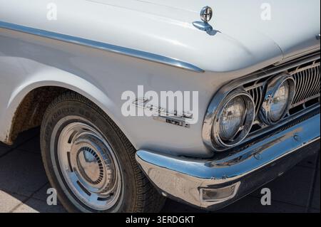 Nahaufnahme des vorderen Kotflügels, des Emblems in Chrom, der Doppelscheinwerfer und des Rads eines klassischen weißen Mercury Comet Custom American Car. Stockfoto
