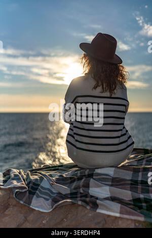 Frau Sonnenuntergang Ozean entspannend auf Klippen und beobachten glitzerndes Meer in der Abenddämmerung Stockfoto