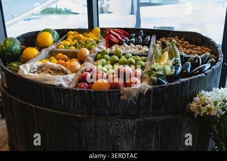 Bunte Auswahl an frischen Produkten, darunter Wassermelonen, Zitronen, Äpfel, Granatäpfel, Auberginen, Mais, Paprika, Walnüsse, Mandeln in einem Pel angeordnet Stockfoto