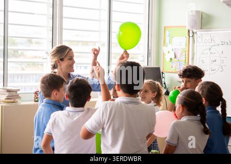 Grundschullehrer, der eine praktische wissenschaftliche Aktivität mit einer Gruppe von Schülern mit Ballons im Klassenzimmer führt. Stockfoto