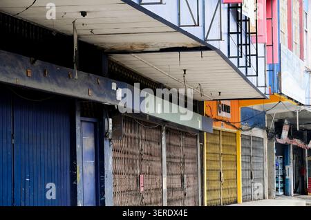 Pekanbaru, Indonesien - 28. September 2025: Traditionelle asiatische Geschäfte mit verwitterten bunten Rollläden und Drähten auf einer städtischen Straße Stockfoto