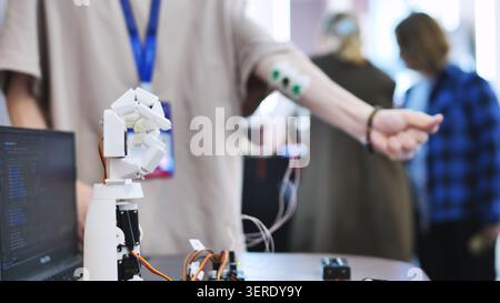 Person, die eine bionische Roboterhand prüft, die von Muskelsensoren gesteuert wird, die mit dem Arm verbunden sind Stockfoto