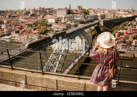 Frau mit Sonnenhut, die auf den Fluss douro, die Brücke und die Altstadt blickt Stockfoto