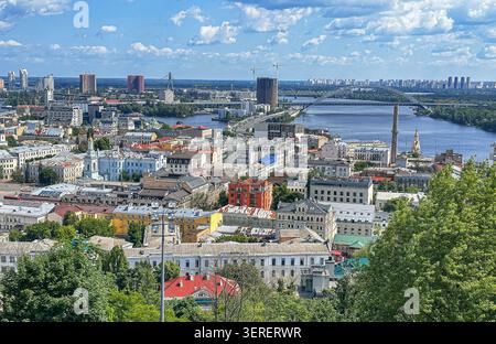 Panoramablick auf das Viertel Podil in Kiew mit dem Fluss Dnieper, historischer Architektur, modernen Hochhäusern und Brücken. Stockfoto
