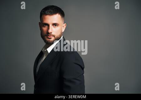 Hübscher junger Mann in schwarzem Anzug, der im Studio posiert. Männliches Schönheitskonzept Stockfoto