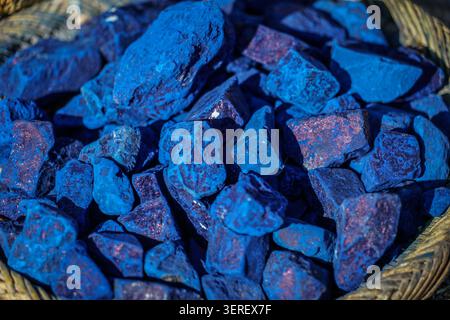 Eine Nahaufnahme eines großen Haufens lebendiger, rauer blauer Mineralstückchen mit rötlich-braunen Einschlüssen. Die rohen, unregelmäßig geformten Steine sind enthalten Stockfoto