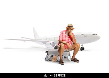 Enttäuschter reifer Tourist sitzt auf einem gepackten Koffer und wartet auf einen Flug isoliert auf weißem Hintergrund Stockfoto