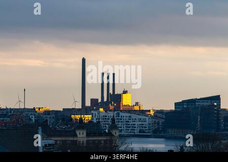 Panoramablick auf den Sonnenuntergang über Kopenhagen, Dänemark mit vorderem Innenhafen und im Hintergrund Sonne, die sehr hell auf die Stromerzeugung scheint Stockfoto