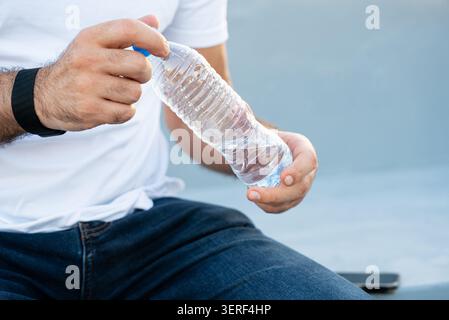 Nahaufnahme der Hand, die leere transparente Kunststoffflasche im Freien drückt Stockfoto