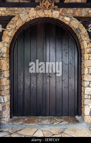 Rustikale Holzbogentür in Steinmauer Stockfoto