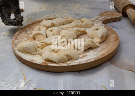 Rohe gedrehte Teigstücke auf Holzbrett bereit zum Backen Stockfoto