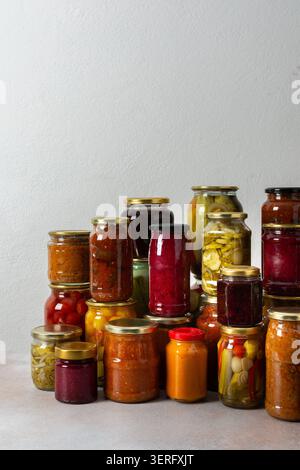 Canning ist eine häufige Aktivität in der Küche, da die Theke mit Gemüse und Obst gefüllte Gläser säumen. Diese Praxis hilft dabei, Lebensmittel für den Gewinn zu bewahren Stockfoto