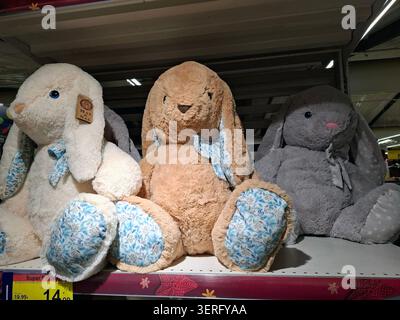 DENIA, SPANIEN - 10. Dezember 2025. Plüschtiere Max & Sax Hasen in weiß, braun und grau sitzen während eines Weihnachtsverkaufs in einem Regal in einem Supermarkt in Spanien. Th Stockfoto