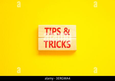 Symbol für Tipps und Tricks. Konzeptwörter Tipps und Tricks auf schönen Holzblöcken. Schöner gelber Hintergrund. Geschäftliche Tipps und Tricks motivieren Stockfoto