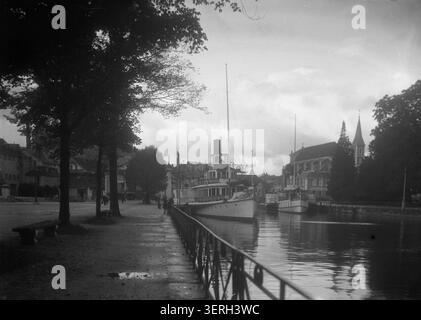 Boote säumen den Quai de la Tournette in Annecy, Haute-Savoie, Frankreich, auf einem Foto von Henri Ferrand aus dem Jahr 1926. Der silberne Gelatinedruck dokumentiert die Aktivitäten am Wasser und die Hafenumgebung des Seehafens. Stockfoto