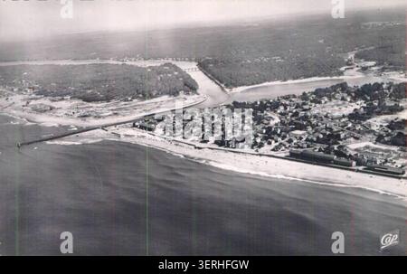 Eine Luftaufnahme zeigt Capbreton entlang der Atlantikküste von Landes, wobei die gebaute Struktur der Stadt an den Hafenrändern und der Küste ausgerichtet ist, in einer Postkartenperspektive aus dem 20. Jahrhundert, die das Layout der Küstensiedlung und die maritime Geographie zeigt. Stockfoto