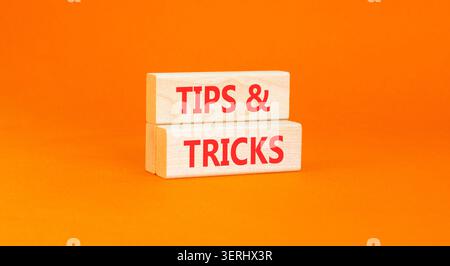 Symbol für Tipps und Tricks. Konzeptwörter Tipps und Tricks auf schönen Holzblöcken. Wunderschöner orangefarbener Hintergrund. Geschäftliche Tipps und Tricks motivieren Stockfoto