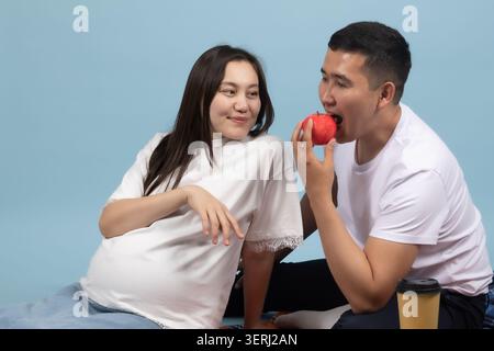 Schwangere Frau und Mann sprechen lächelnd auf blauem Hintergrund Stockfoto