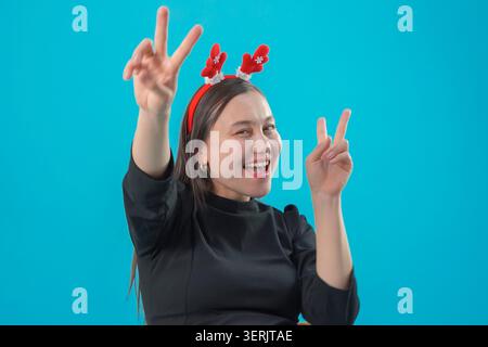 Frau, die Siegeszeichen mit beiden Händen im Studio macht Stockfoto