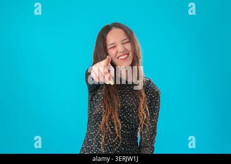 Junge Frau, die mit dem Finger im Studio auf die Kamera zeigt Stockfoto