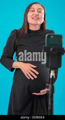 Schwangere Frau, die ihren Bauch vor der Kamera hält Stockfoto