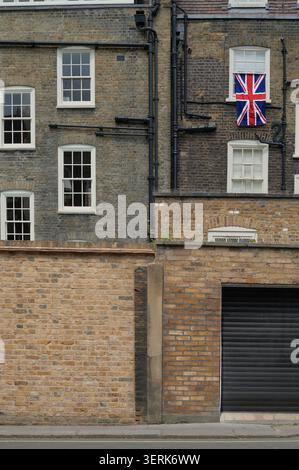Union Jack Union Flag UK Flagge hängt am Fenster hinter dem alten Reihenhaus Stockfoto