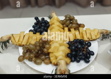 Frische Ananasscheiben, sternförmig angeordnet. Pralle Trauben umgeben das Herzstück der Früchte. Süß und süß, diese Platte verwöhnt das Auge. Perfekt für Stockfoto
