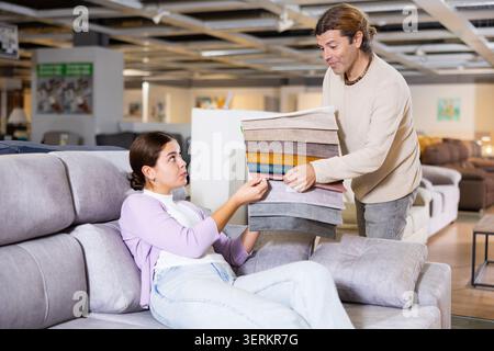 Der Mann präsentiert einer Frau Polstermuster Stockfoto