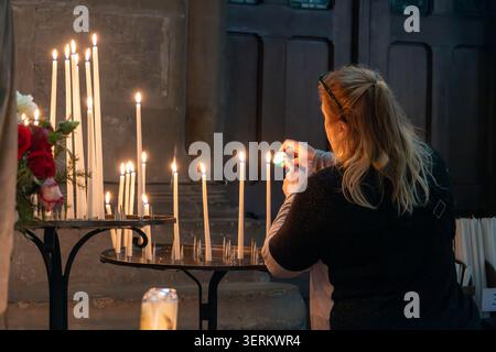 Nahaufnahme eines Besuchers, der eine Votivkerze an einem Kerzenstand in der Kathedrale Notre-Dame de Reims, Reims, Grand Est, Frankreich anzündet. Stockfoto