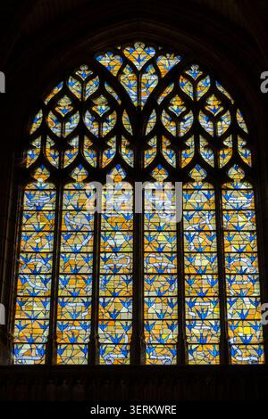 Nahaufnahme eines Buntglasfensters mit geometrischem Muster in Blau und Gold in der Basilique Saint-Remi, Reims, Frankreich. Stockfoto