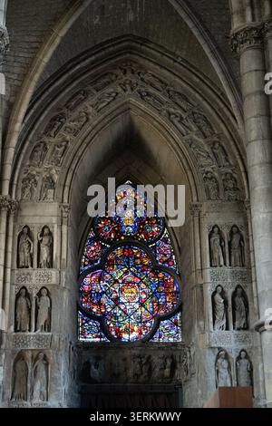 Spitzer gotischer Bogen mit geschnitzten Steinfiguren und Buntglas in der Kathedrale Notre-Dame von Reims, Reims, Grand Est, Frankreich. Stockfoto