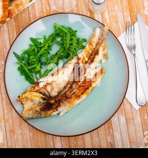 Frisch gebackener Fisch Seebarsch mit Rucola Stockfoto